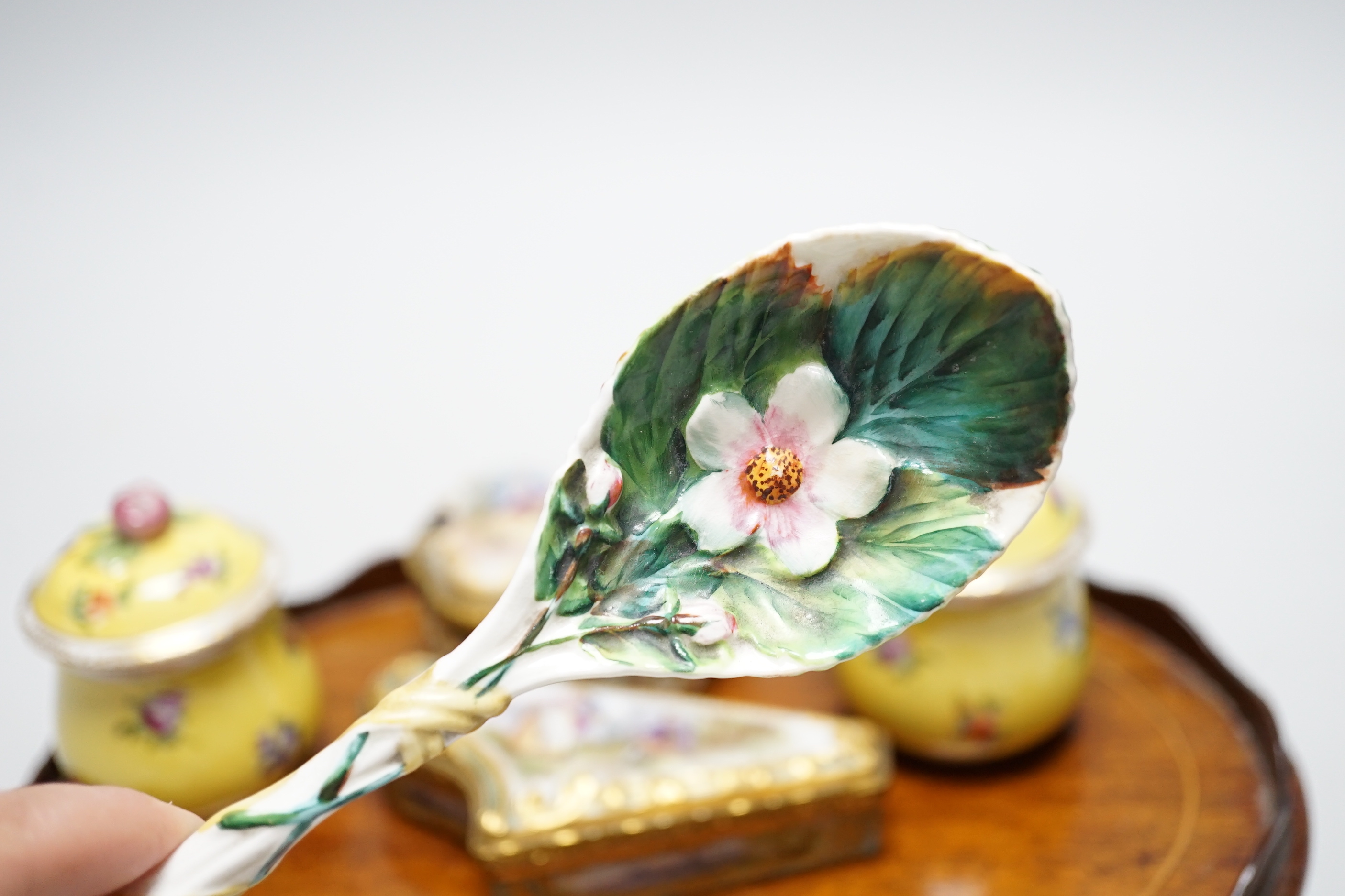 A small oval mahogany tray and German decorative porcelain cups and covers, two trinket boxes and a spoon